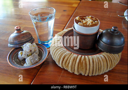 Türkischer Kaffee mit Haselnuss in eine Schale von einer Kupfer Deckel versehen und auf einem weichen Getränkehalter ähnelt einem Pascha hat serviert. Stockfoto