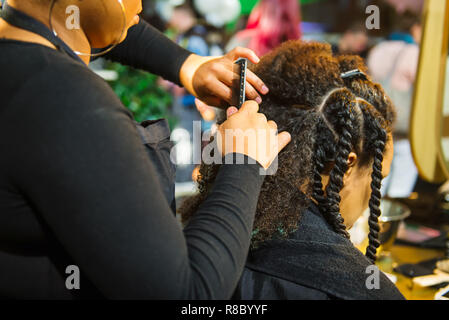 Nahaufnahme der Afrikanischen hairstylist geflochtenes Haar der afro-amerikanische Frauen Client im Friseur Salon. Schwarz gesundes Haar Kultur und Stil. Stilvolle Therapie pr Stockfoto