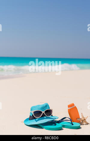 Sonnencreme-Flaschen, Schutzbrille, Seesterne und Sonnenbrille auf weißem sand Strand Hintergrund Ozean Stockfoto