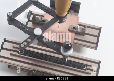 Gravur Gerät Stromabnehmer mit CNC-graveur mit Buchdruck Alphabet auf weißem Hintergrund Stockfoto