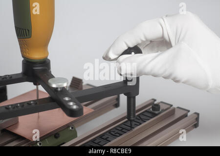 Arbeiter Hände an Gravur Gerät Stromabnehmer mit CNC-graveur mit Buchdruck Alphabet auf weißem Hintergrund Stockfoto