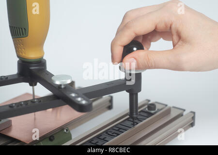 Arbeiter Hände an Gravur Gerät Stromabnehmer mit CNC-graveur mit Buchdruck Alphabet auf weißem Hintergrund Stockfoto