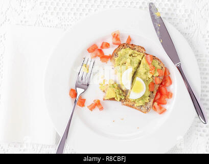Essen avocado auf Toast mit Ei und Tomaten. Stockfoto