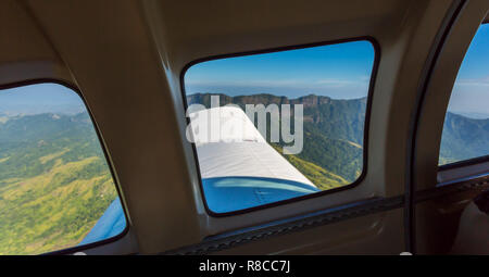 Atemberaubende Aussicht auf die Bergkette aus einem Fenster von einem kleinen Flugzeug während weg nehmen. Flugreisen in Fidschi, Melanesien, Ozeanien. Grün der üppigen Vegetation auf em Stockfoto