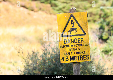 Gelbes schild Warnung vor Gefahr strom Overhead Stockfoto