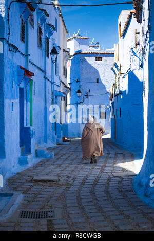Ein Mann mit einem traditionellen Kleid ist zu Fuß in der schönen blauen Medina von Tanger, Marokko. Stockfoto