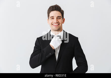 Porträt von einem gutaussehenden jungen Mann Kellner tragen Tuxedo und Handschuhe, die auf weißem Hintergrund Stockfoto