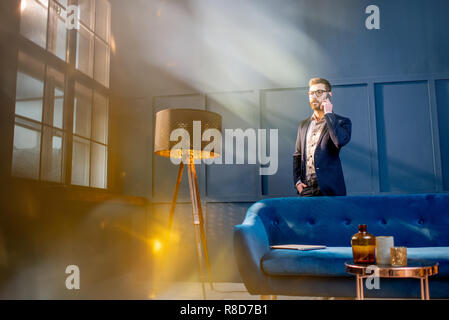 Porträt eines eleganten Geschäftsmann sitzt mit Laptop auf der Couch im Luxury blue Office Interior Stockfoto