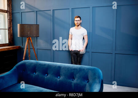 Porträt eines Mannes im weissen T-Shirt auf der blauen Wand Hintergrund im Luxus zu Hause oder im Büro intreior Stockfoto