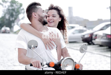 Glückliches junges Paar reiten einen Roller in der Stadt an einem sonnigen Tag Stockfoto