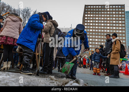 Öffentliche Beamte gefrorener Schnee schaufeln in Odori Park, Central Sapporo. Hokkaido, Japan. Stockfoto