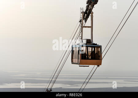 Seilbahn Lifte Touristen auf den Berg Festung Masada. Standseilbahn auf dem Hintergrund der judäischen Wüste, das Tote Meer und den bewölkten Himmel. Wüste Stockfoto