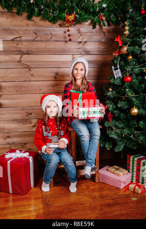 Frohe Weihnachten und schönen Urlaub. Zwei süße kleine Kind Mädchen mit Geschenk Geschenk Boxen in der Nähe von Tree indoor Stockfoto