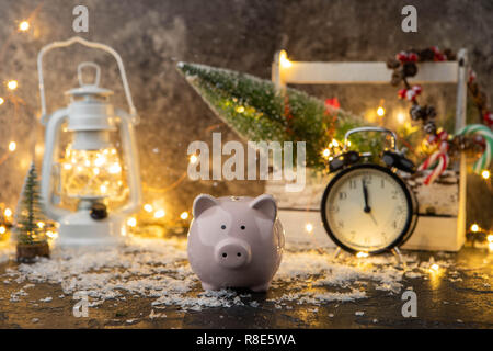 Foto von piggy Bank, Weihnachtsdekoration, Holzkiste, rote Kerzen, Schnee, brennende Girlanden Stockfoto