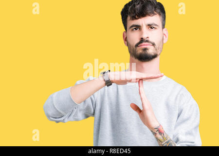 Jungen gutaussehenden Mann mit Sweatshirt über isolierte Hintergrund tun time out Geste mit den Händen, frustriert und ernstes Gesicht Stockfoto