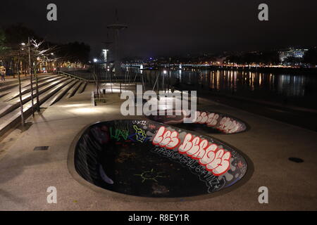 Ein flußufer Skate Park in Graffiti bedeckt am Ufer des Flusses Rhône in Lyon, Frankreich in der Nacht. Stockfoto