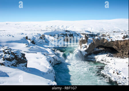 Wilde Wasser der Skjalfandafljot Fluss in den Godafoss Wasserfall fließt. Wirbelnde türkisfarbenes Wasser, Schnee gefrorene Landschaft, felsigen Hintergrund Stockfoto