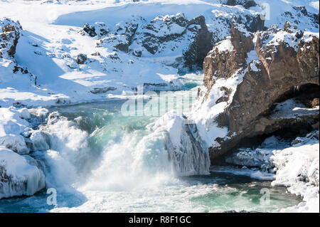 Wilde Wasser der Skjalfandafljot Fluss in den Godafoss Wasserfall fließt. Wirbelnde türkisfarbenes Wasser, Schnee gefrorene Landschaft, felsigen Vordergrund Stockfoto