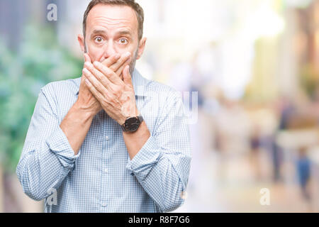 Mittleres Alter hoary Senior Business Mann über isolierte Hintergrund schockiert über den Mund mit Händen für Fehler. Geheime Konzept. Stockfoto