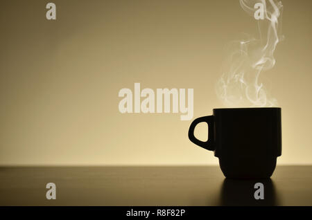 Silhouette heißen Kaffee Tasse mit Dampf in der Nähe der hellen beigen Hintergrund Stockfoto