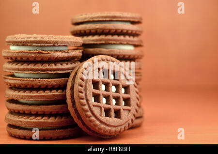 Haufen Chocolate Chip Cookies mit Weiße Vanille Creme gefüllt liegt auf Holz- braune Oberfläche. Süßes und leckeres Sandwich runde Kekse. Detaillierte essen Ph Stockfoto