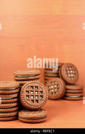 Haufen Chocolate Chip Cookies mit Weiße Vanille Creme gefüllt liegt auf Holz- braune Oberfläche. Süßes und leckeres Sandwich runde Kekse. Detaillierte essen Ph Stockfoto