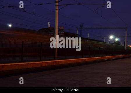 Die Ukrainische s-bahn eilt entlang der Bahnstrecke in der Nacht. Motion Effekt Stockfoto