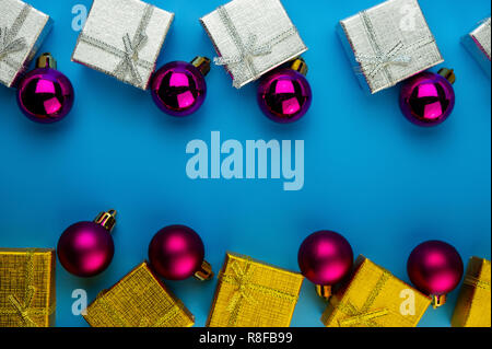 Festliche lila Bälle silbernen und goldenen Geschenkboxen auf blauem Hintergrund. Weihnachten Komposition. Stockfoto