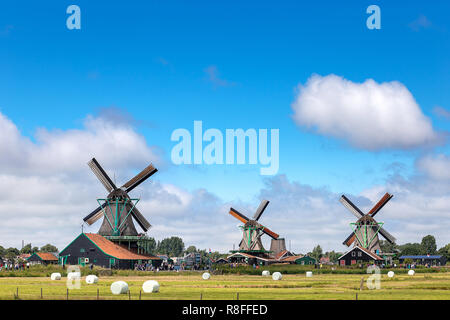 Alte und klassische holländische Windmühle in Zaanse Schans, wo ist die berühmteste Sehenswürdigkeit für Touristen in der traditionellen und der Natur mit Kanal und den blauen Himmel zu reisen i Stockfoto