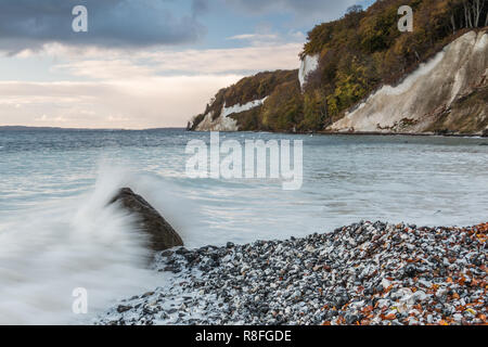 Kreidefelsen am Morgen mit dramatischen Wolken im Nationalpark Jasmund auf der Insel Rügen. Wave Hits über einen Stein. Weißes Wasser auf den Strand Stockfoto