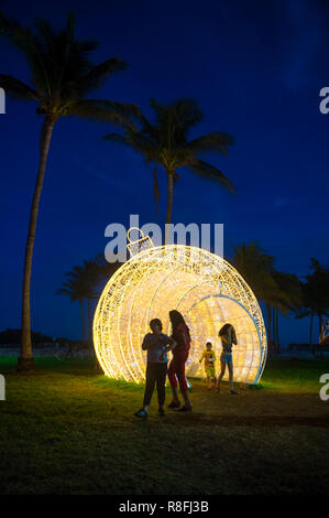 MIAMI - Dezember, 2017: Urlaub Besucher nehmen Bilder vor einem übergroßen Christmas ornament Als saisonale Attraktion in der Lummus Park. Stockfoto
