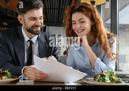 Geschäftsleute in Business Lunch im Restaurant sitzen Essen diskutieren Vertrag heiter Stockfoto