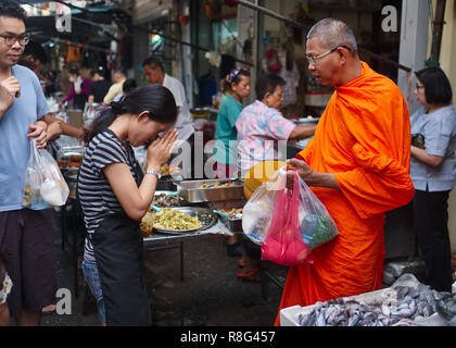 Ein buddhistischer Mönch in einem Street Market in Bangkok, Thailand, geehrt wird mit einem üblichen Wai, eine respektvolle Thailändische Gruß oder eine Geste des Respekts Stockfoto