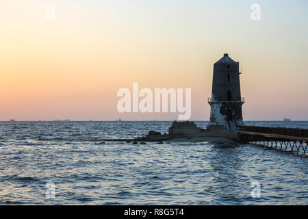 Der alte Leuchtturm mit einer Bridge bei Sonnenuntergang, Foto vom Ufer, Alexandria, Ägypten Stockfoto