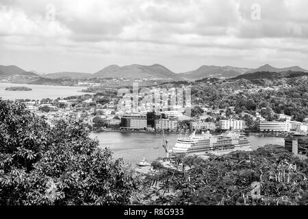 Castries, St. Lucia - 26. November 2015: Schiff vertäut im Hafen auf die Berglandschaft. Hafen und Stadt an bewölkten Himmel. Luxus Reisen auf dem Boot, Wasser transportieren. Ferienhäuser auf der Insel. Stockfoto