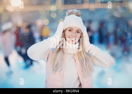 Portrait Junge lächelnd weibliche Hände halten in der Nähe der Leiter in weiße Handschuhe, Pullover, Hut und rosa Jacke auf der Eisbahn Stockfoto