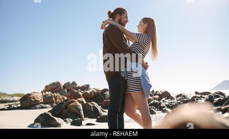 Romantisches Paar umarmt am felsigen Strand. Mann und Frau stehen zusammen und an einander mit der Liebe. Stockfoto