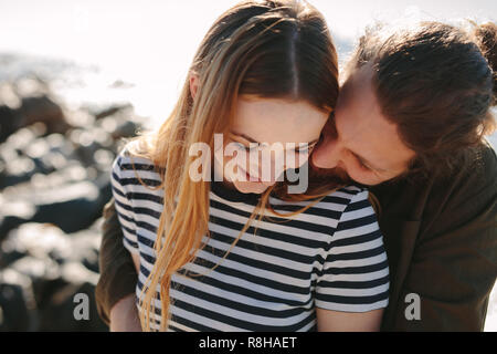 Romantisches Paar genießt jeder des anderen Firma auf ihren Urlaub am Strand. Mann umarmt seine Frau von hinten und lächelnd entlang der Küste. Stockfoto