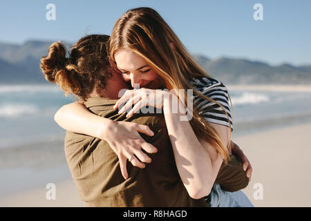 Romantisches Paar umarmen draußen am Strand. Schöne Frau umarmt ihren liebevollen Freund am Strand. Stockfoto