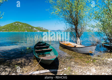 Zwei kleine Schiffe auf ein Indigo tropischen Strand suchen. Szenische Ansicht vom Skutarisee, Montenegro Stockfoto