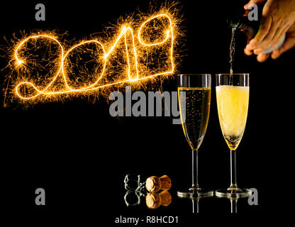 Frohes Neues Jahr zwei Gläser Champagner und schöne goldglänzenden Zahlen 2019 mit Schein Feuerwerk auf schwarzem Hintergrund in neue Y-isolierten geschrieben Stockfoto