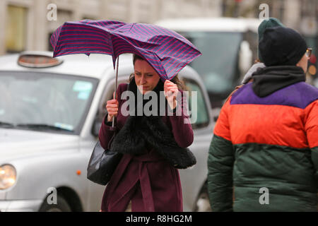 London, Großbritannien. 15. Dez 2018. Eine Frau kämpft mit einem Regenschirm bei einem nassen, kalten, stürmischen Tag in London Quelle: Dinendra Haria/Alamy leben Nachrichten Stockfoto