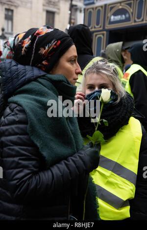 Paris, Frankreich, 15. Dezember, 2018. Frauen, die in der Menge, die eine Rose als Symbol des Friedens, place de l'Opéra. Rund 2.000 Demonstranten in gelben Westen ('Gilets Jaunes') demonstrierten in Paris gegen Steuererhöhungen und Kaufkraft Verluste für den fünften Samstag in einer Reihe. Credit: Christelle Chanut/Alamy leben Nachrichten Stockfoto