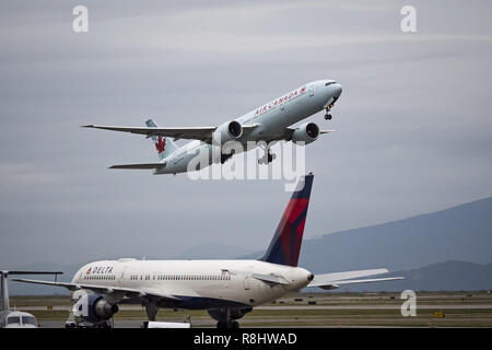 Richmond, British Columbia, Kanada. 25 Okt, 2017. Eine Air Canada Boeing 777-300ER C-FNNU) wide-Body Jet Airliner zieht aus Vancouver International Airport. Im Vordergrund: eine Delta Air Lines Boeing 757 auf dem Asphalt geparkt. Credit: bayne Stanley/ZUMA Draht/Alamy leben Nachrichten Stockfoto