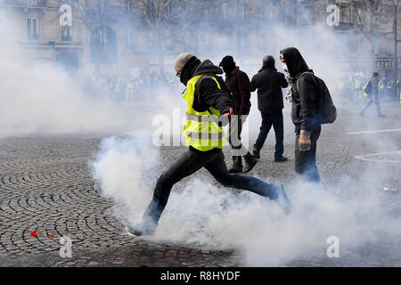 Paris, Frankreich. 8 Dez, 2018. Eine Demonstrantin tritt eine Träne Shell in der Nähe des Arc de Triomphe in Paris, Frankreich, am 8. Dezember, 2018. Credit: Chen Yichen/Xinhua/Alamy leben Nachrichten Stockfoto