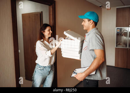 Weibliche Kunden und Lieferung Junge prüft, Pizza, schnellen Service. Kurier aus Pizzeria und die Frau an der Tür Stockfoto