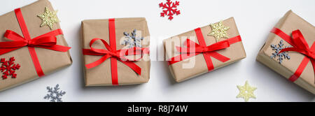 Winterurlaub Konzept, Weihnachten Geschenke verpackt in Handwerk Papier mit rotem Band und Schneeflocken, Ansicht von oben Stockfoto