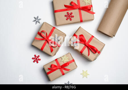 Winterurlaub Konzept, Weihnachten Geschenke verpackt in Handwerk Papier mit rotem Band und Schneeflocken, Ansicht von oben Stockfoto
