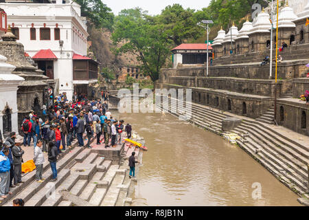 Leute beobachten ein Hindu Beerdigung auf der Ghat auf den Bagmati River am Heiligen hinduistischen Pashupatinath Tempel in Kathmandu, Nepal Stockfoto