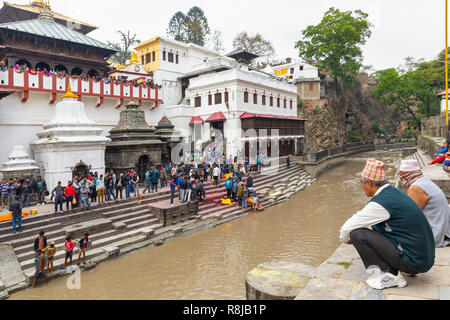 Leute beobachten ein Hindu Beerdigung auf der Ghat auf den Bagmati River am Heiligen hinduistischen Pashupatinath Tempel in Kathmandu, Nepal Stockfoto